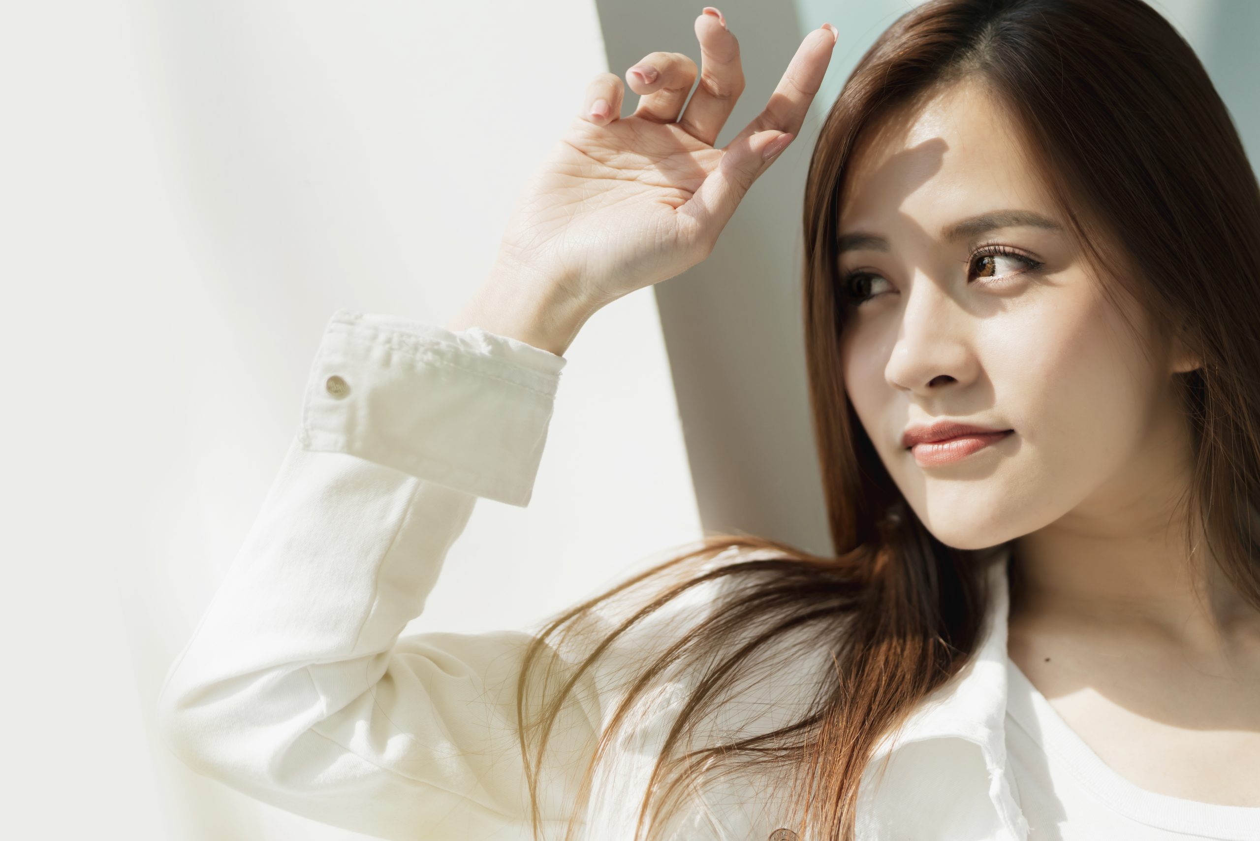 抬手遮陽的棕髮亞洲女子